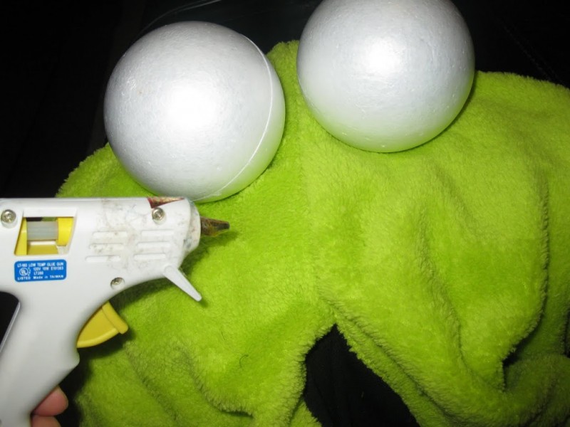 Using hot glue to attach styrofoam balls to create eyes on the Yip Yip Costume.