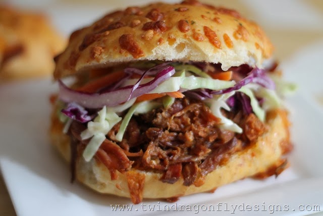 Pulled pork sandwich with coleslaw on a white plate.