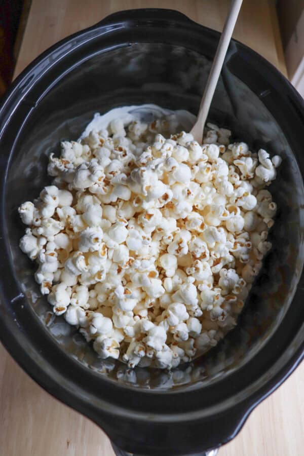 Black crockpot filled with popcorn and white chocolate.
