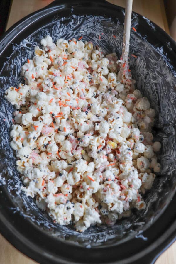 Black crockpot with chocolate covered popcorn.