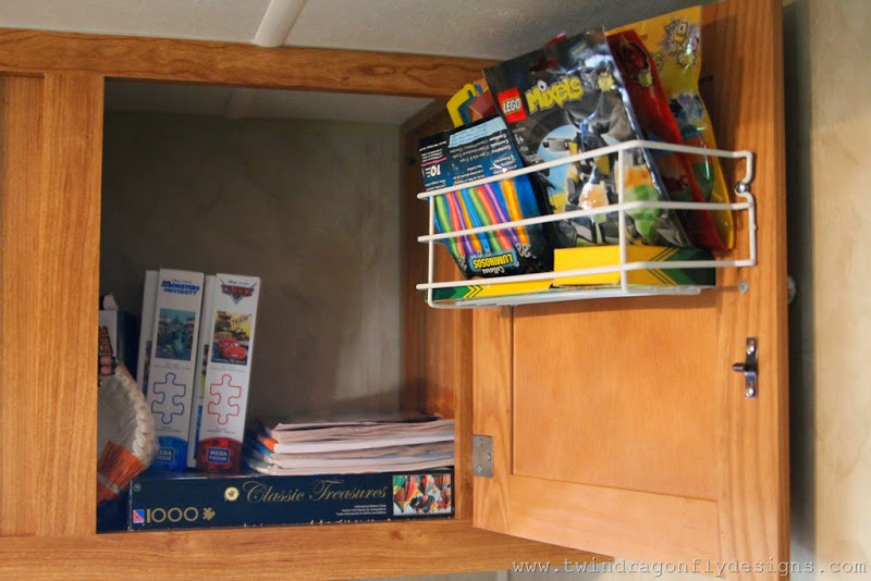 Wire shelves attached to a travel trailer cupboard door to hold smaller items.