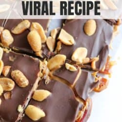 Close-up of chocolate Snickers date bark topped with peanuts. The bark is cut into pieces and placed on parchment paper. Text overlays read, Snickers Date Bark Viral Recipe and homemadeheather.com.