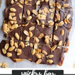 Overhead view of chocolate snickers date bark topped with peanuts, sliced into squares. Text on image reads Snickers Bar Viral Date Bark.