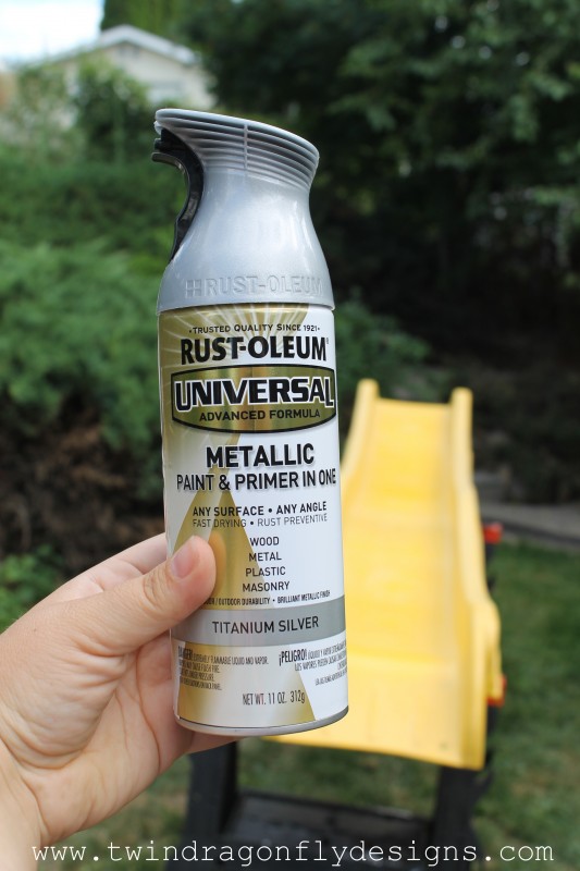 A close up of Rustoleum metallic spray paint, with a yellow playground slide in the background.