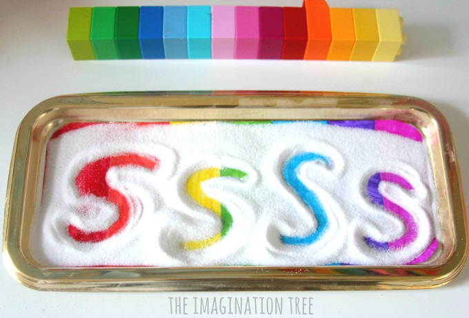 20+ Sensory Crafts for Kids A tray painted with rainbow colors is covered with sugar and the letter S is written with a finger.