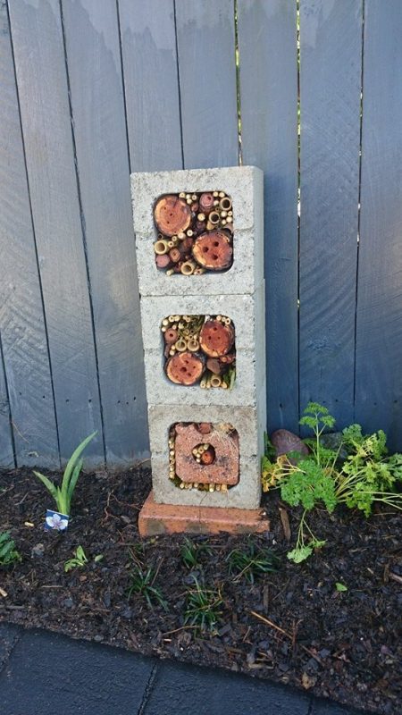 Bee House made of bricks and hallow tubes with a fence in the background.