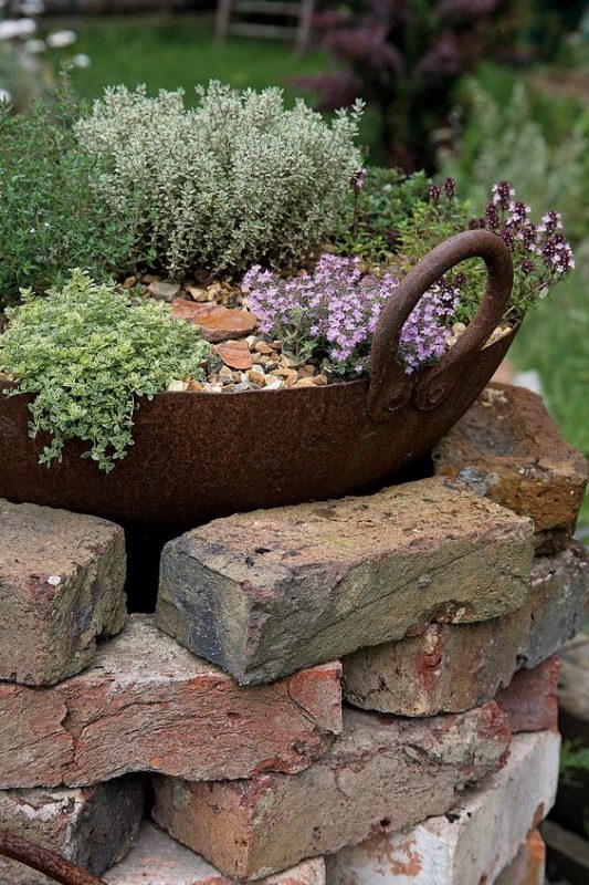 Rocks stacked into a garden with purple flowers.