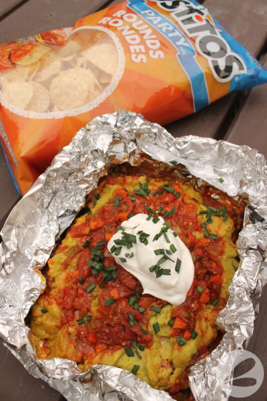 Layers of ground beef, salsa, guacamole and sour cream in a foil packet.