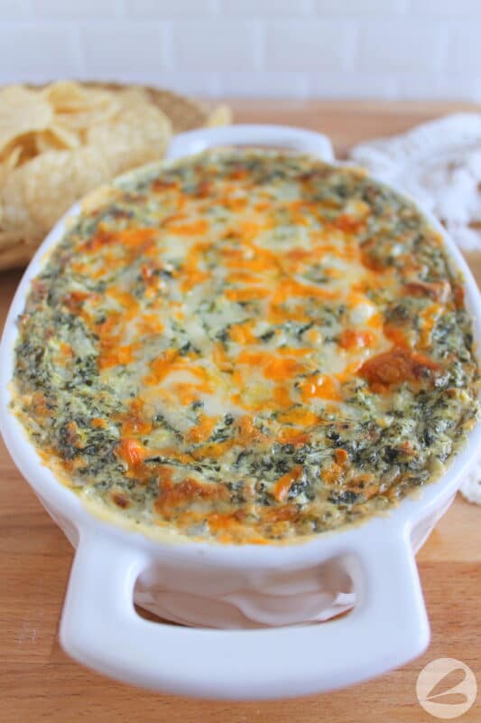 A casserole dish is filled with a baked spinach dip recipe.