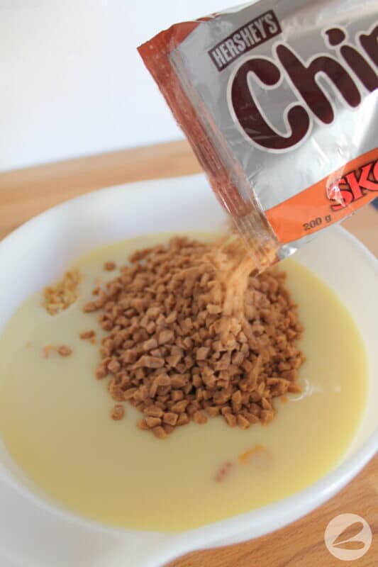 Adding Skor bits into the bowl of crushed Ritz crackers and sweetened condensed milk.