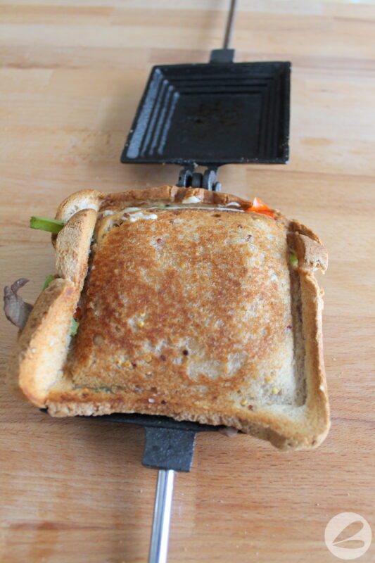 Pie iron open to show philly cheesesteak sandwich inside.
