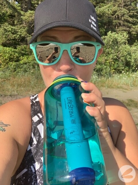 Heather with blue sunglasses on sipping on a blue life straw in a blue nalgene water bottle.