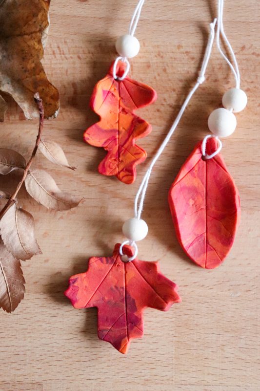 Polymer clay leaf ornament with white twine hanger.