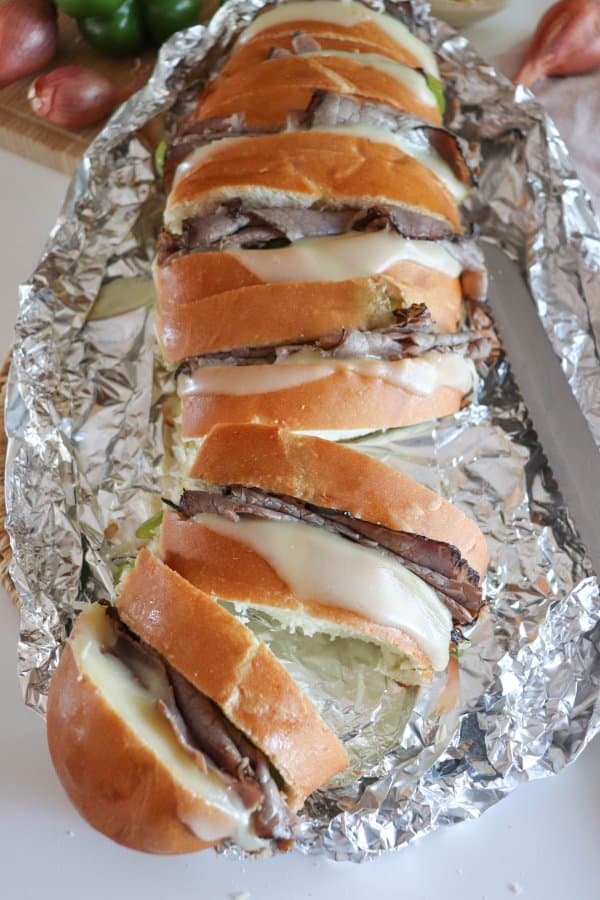 Campfire Philly Cheesecake Sandwich on foil with green bell pepper, roast beef and melted white cheese between slices of french bread.