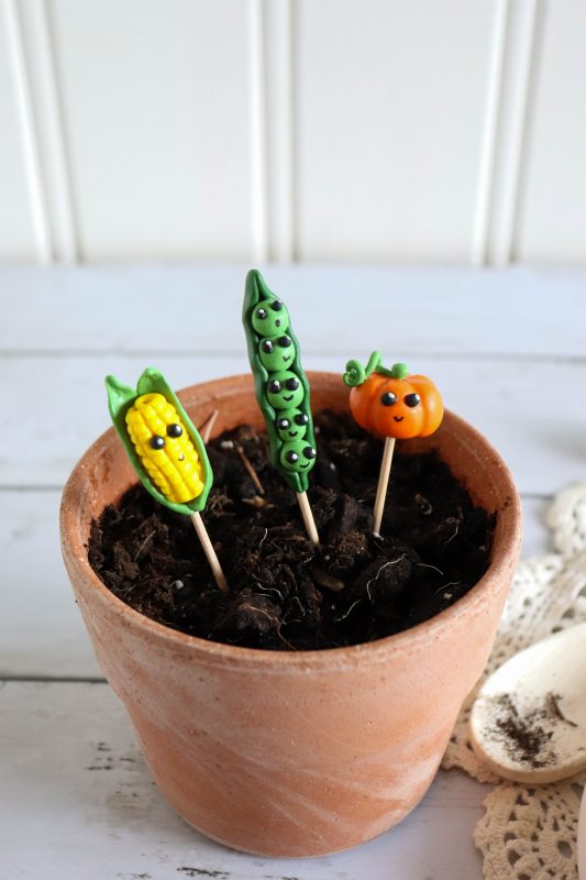 Clay vegetable plant markers in a terracotta pot.