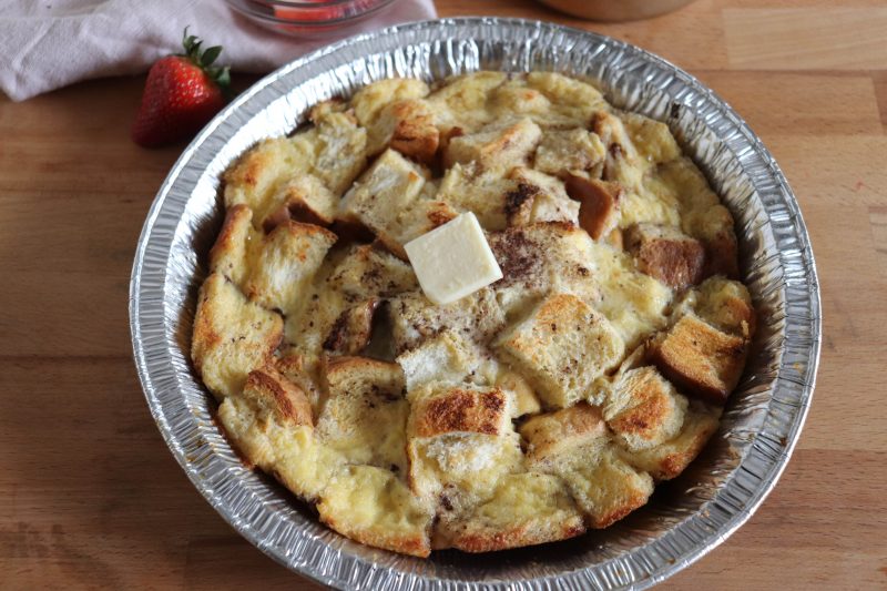 Foil packet french toast bake in a foil pie plate topped with a square of butter.