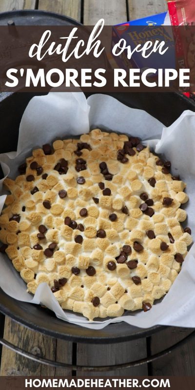 Toasted mini marshmallows and melted chocolate chips in a parchment paper lined cast iron dutch oven on a wooden picnic table.