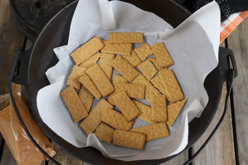 Graham crackers layered in the bottom of a parchment paper lined dutch oven.