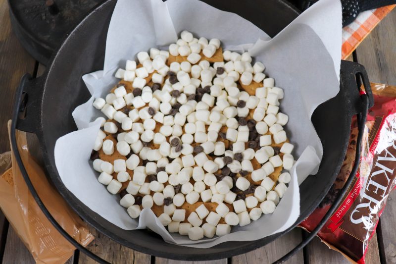 Graham crackers, chocolate chips and mini marshmallows layered in the bottom of a parchment paper lined dutch oven.