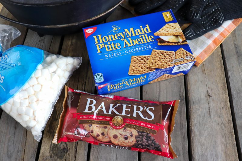 Ingredients for dutch oven smores on a wooden picnic table.