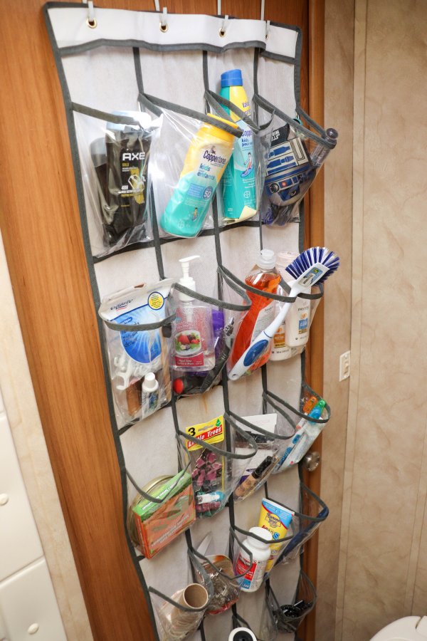 A shoe organizer hanging on is hanging on a travel trailer wall to hold toiletries.