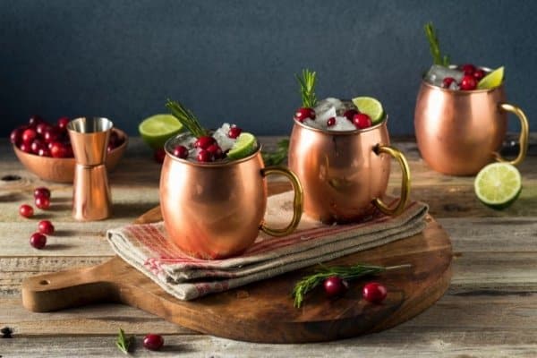 keto mojito recipe Christmas Moscow Mule in two copper cups on a wooden cutting board.