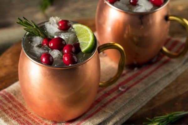 keto mojito recipe Christmas Moscow Mule in a copper mug with cranberries, a lime wedge and rosemary garnish.
