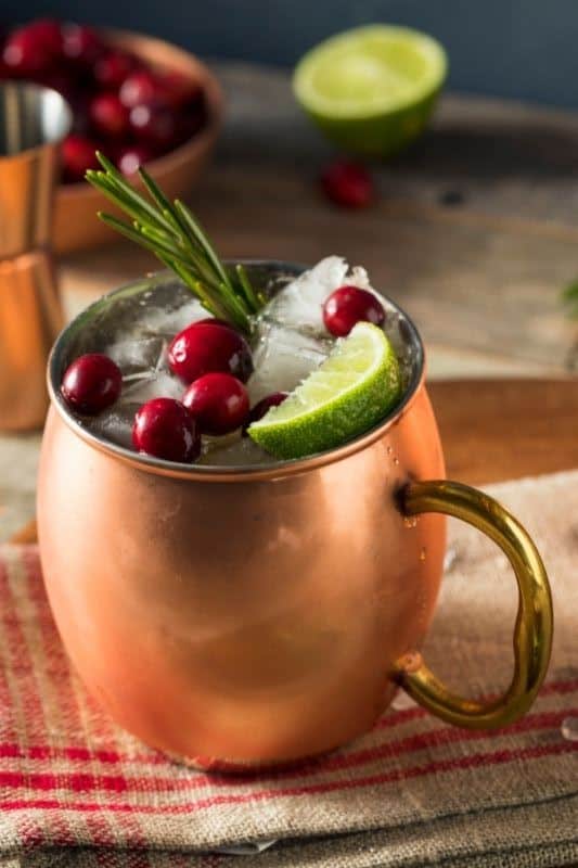 keto mojito recipe Christmas Moscow Mule in a copper mug with cranberries, a lime wedge and rosemary garnish.