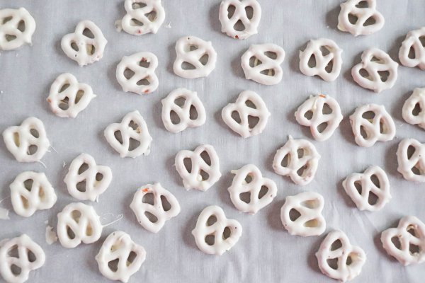 Pretzels covered in white chocolate on parchment paper.