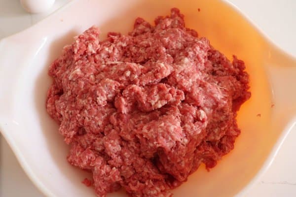 Raw ground pork and ground beef in a white mixing bowl.