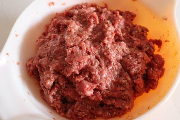 Smoked burger raw meat mixture mixed in a white bowl.