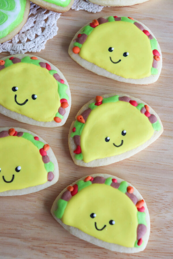 Taco Sugar Cookies with royal icing and a smiley face drawn on with a black food marker.