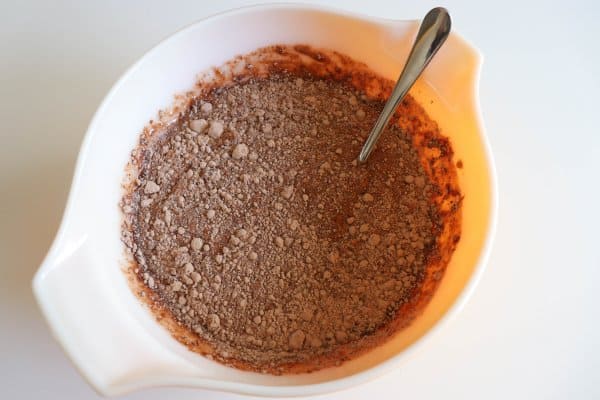 Chocolate cake ingredients being mixed in a large white bowl.