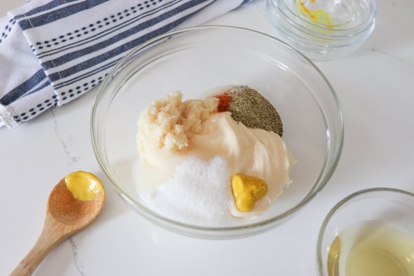 Ingredients for alabama white sauce in a medium mixing bowl on a white counter.