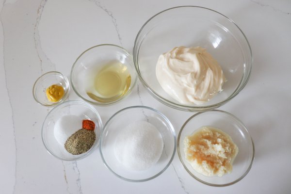 Ingredients for Alabama bbq sauce in clear glass bowls on a white counter.