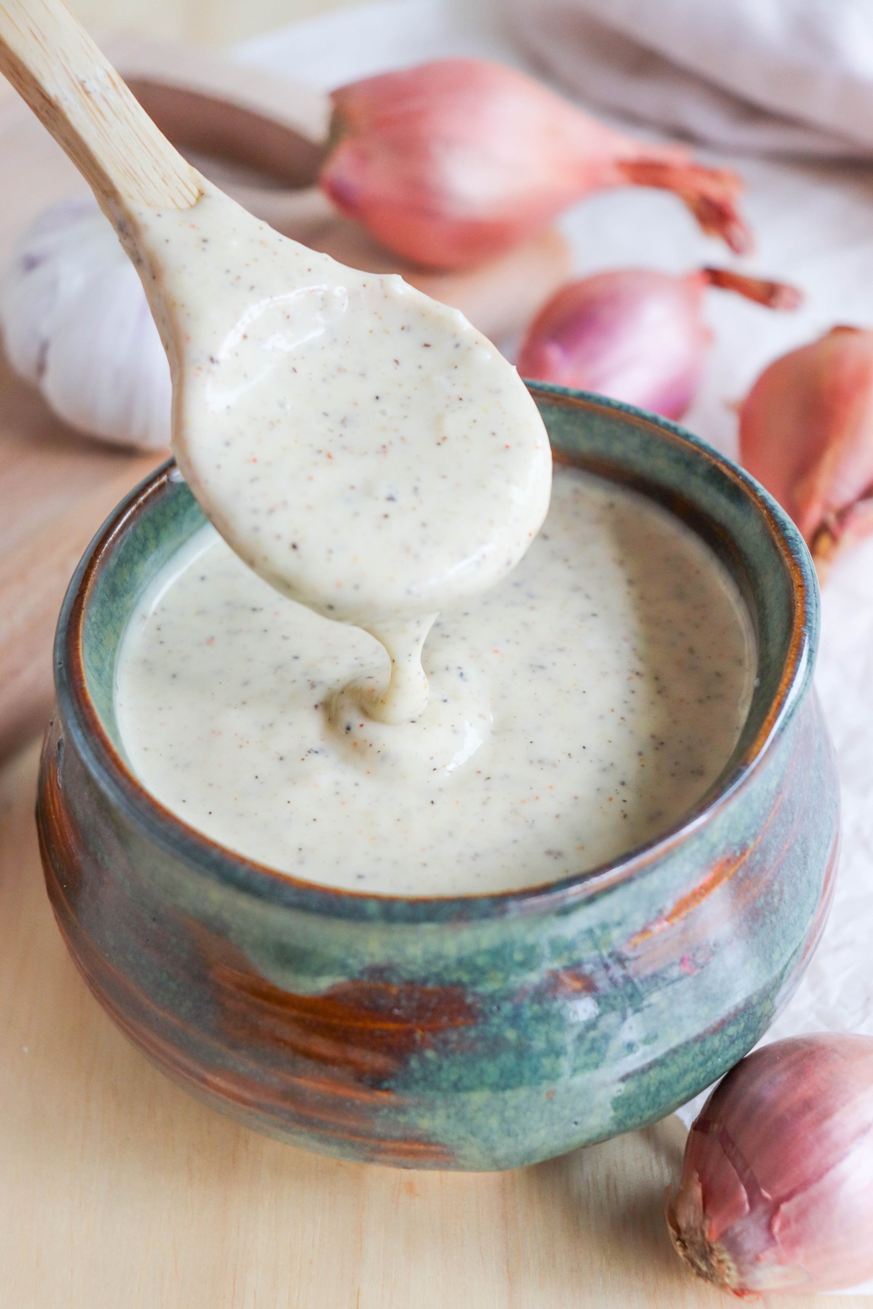 Alabama White Sauce Recipe in a blue dish with a wooden spoon.