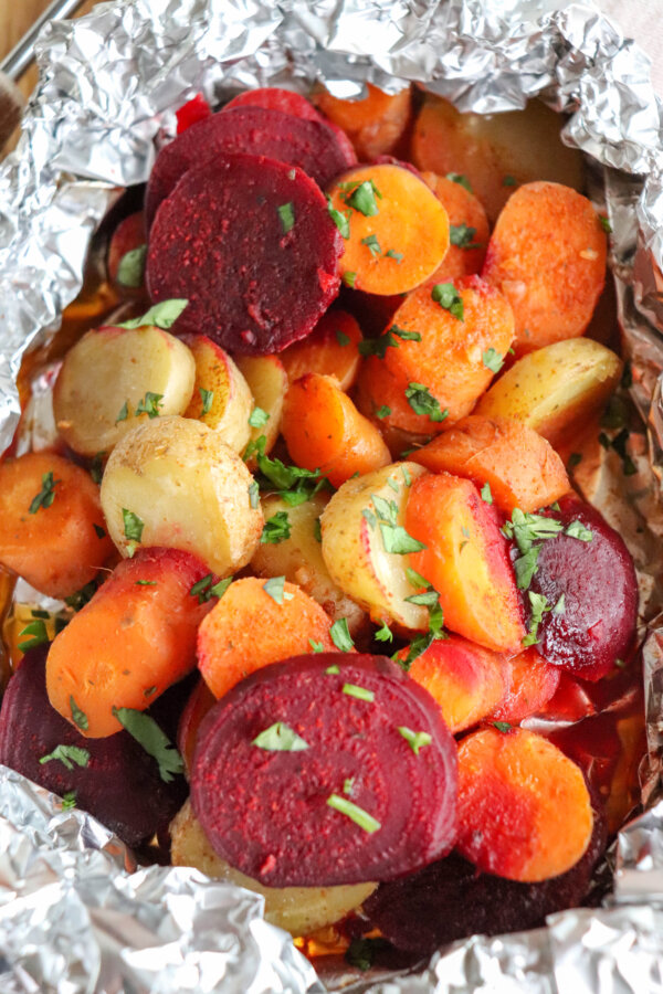 Rounds of beets, white potatoes and carrots cooked in a foil packet and topped with fresh parsley.