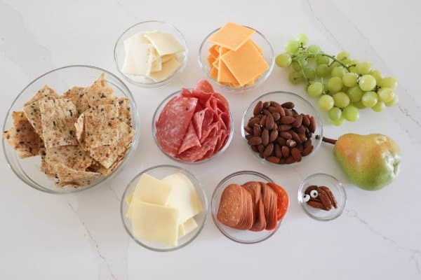 Turkey Charcuterie Board Ingredients in clear glass bowls on a white counter.