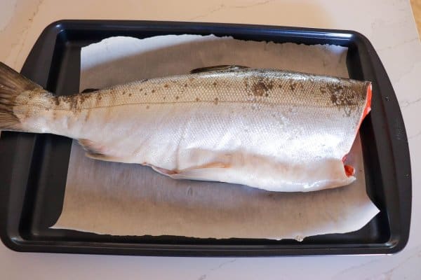 Large salmon fillet on a baking sheet.