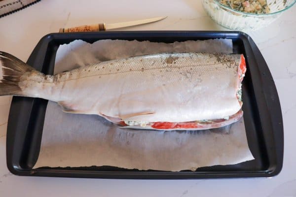 Raw Stuffed Salmon on a parchment paper lined cookie sheet.