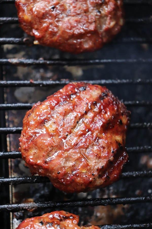 Cooked BBQ hamburger on the grill grate of a barbecue.