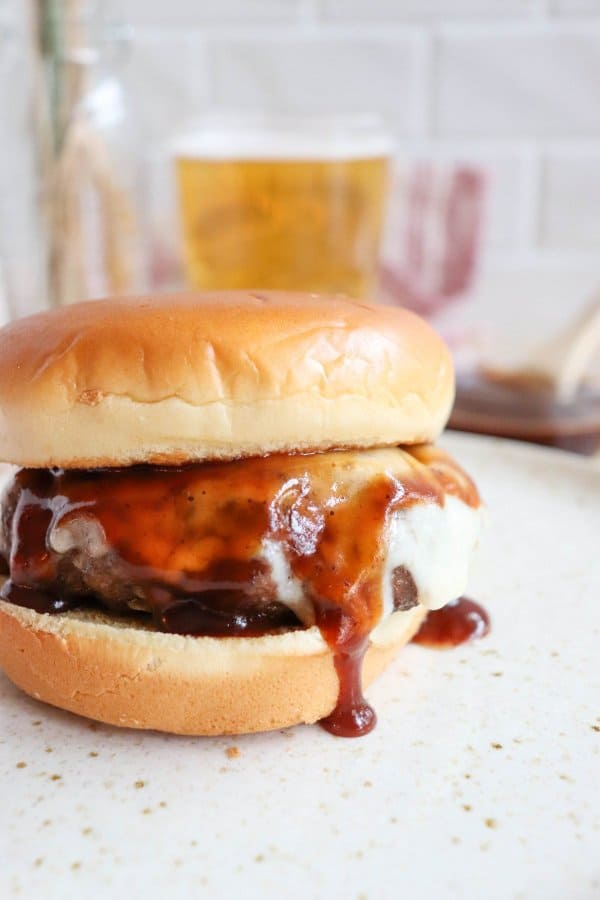 Close up of Barbecue Hamburger with white melted cheese and BBQ sauce on a white bun.
