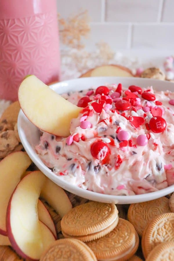 An apple slice is dipped in a Valentine's Day Dessert Dip Recipe.