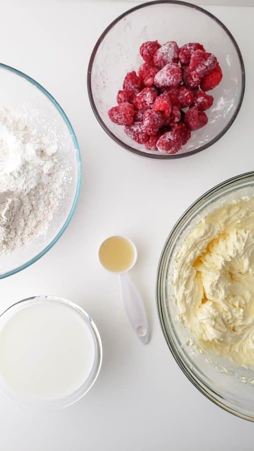 Raspberries, dry cake ingredients, and wet ingredients in separate bowls.