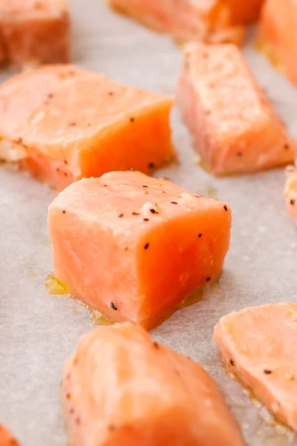 Raw cubed salmon on a baking sheet.