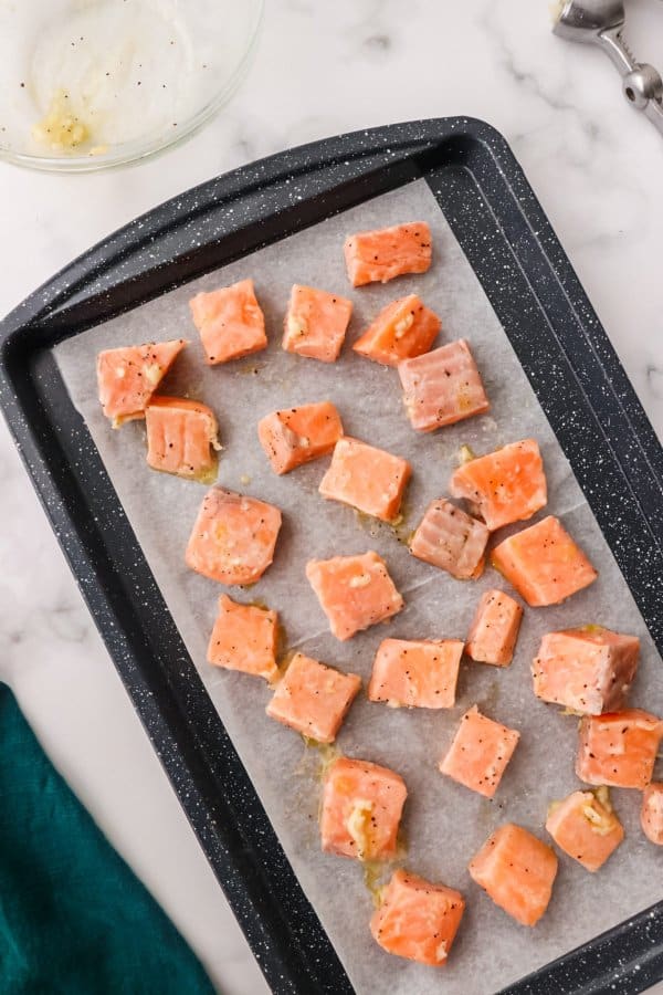 Raw Cubed salmon on a baking sheet.