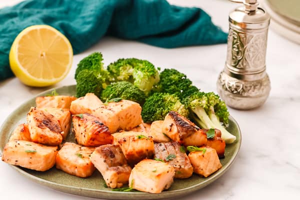 Salmon bites on a green plate with broccoli.