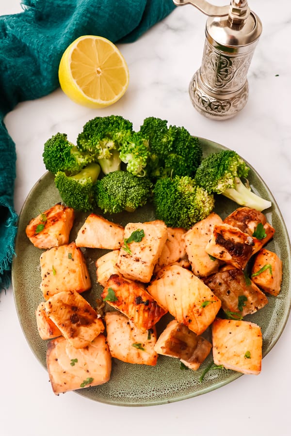 Salmon bites on a green plate with broccoli.