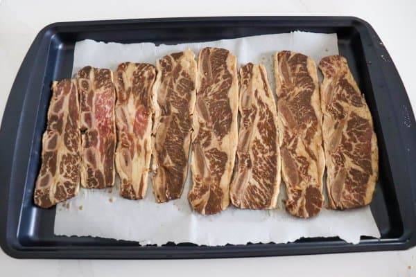 Marinated beef short ribs on a tray to bake.