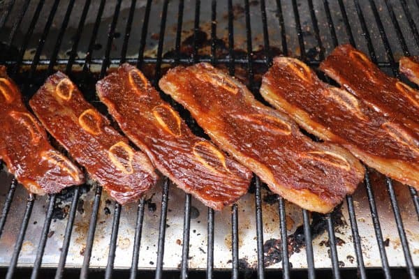 Basted short ribs on a grill.